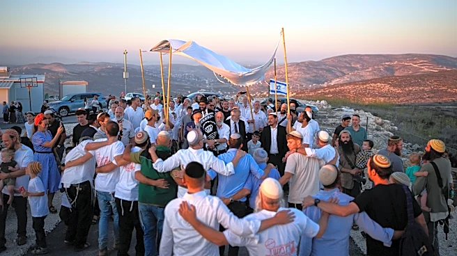 Israeli settlers, some armed, celebrate a new synagogue in the occupied West Bank, in photos