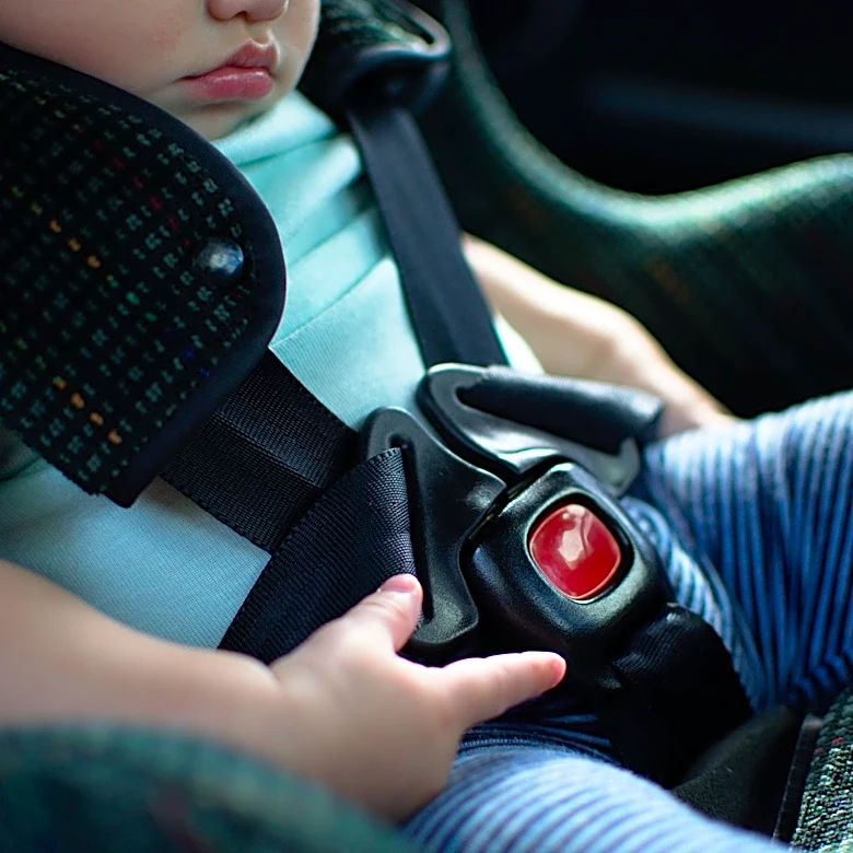 Can a child ride in the passenger seat of a 2-seater car?