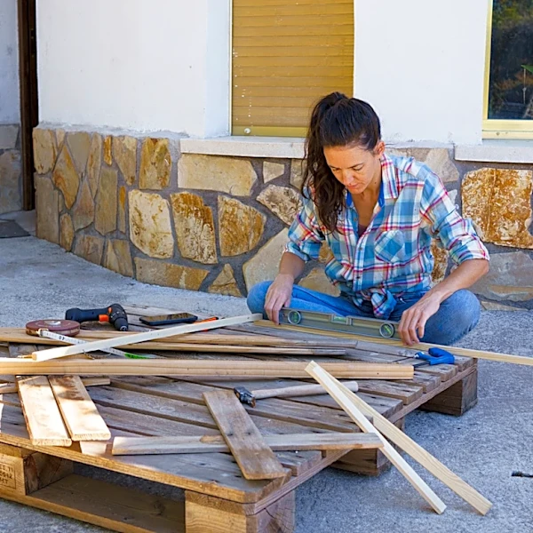 Woman Replaces Concrete Slabs With Old Wood Pallets For A DIY Deck With A Rustic Touch