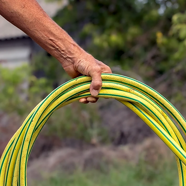 Use A Wire Hanger To Keep Garden Hoses Neat & Organized