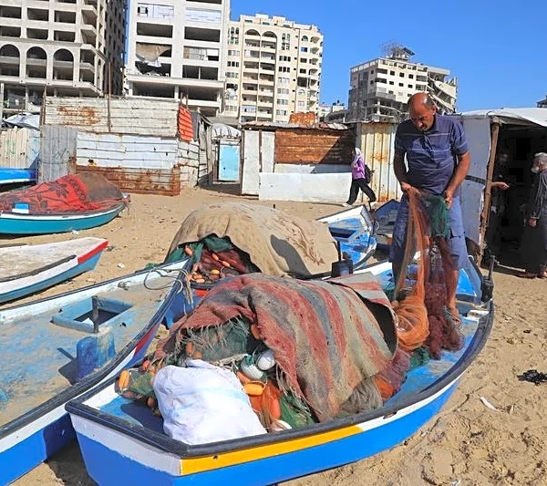 Gazan fishermen patch up dinghies with door frames to keep themselves afloat